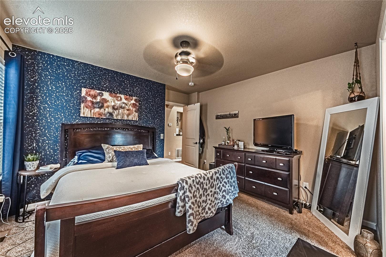 Bedroom featuring ceiling fan, light colored carpet, a textured ceiling, and wallpapered walls