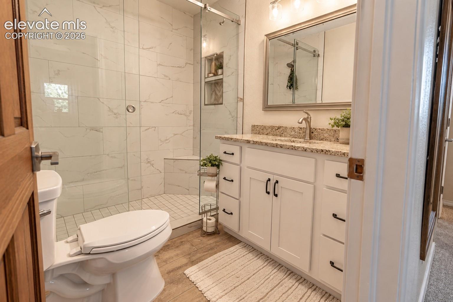 White vanity with granite countertop, undermount sink, and brushed nickel faucet