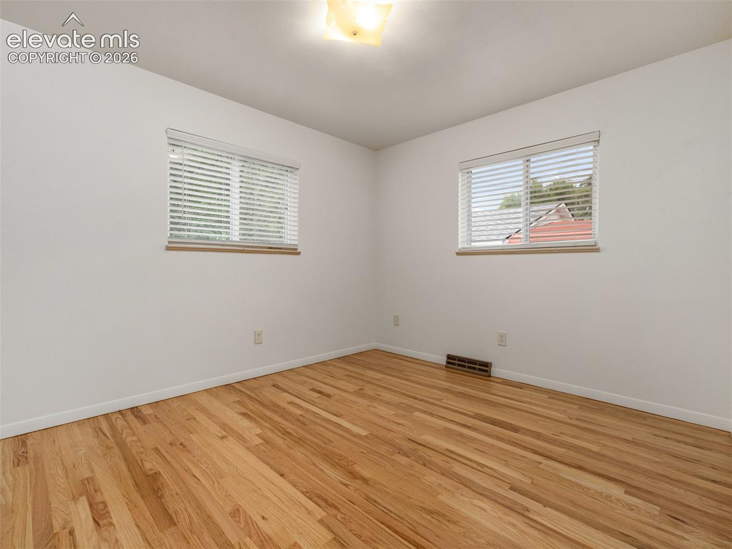 Hardwood flooring throughout, two windows with blinds, and flush-mount lighting