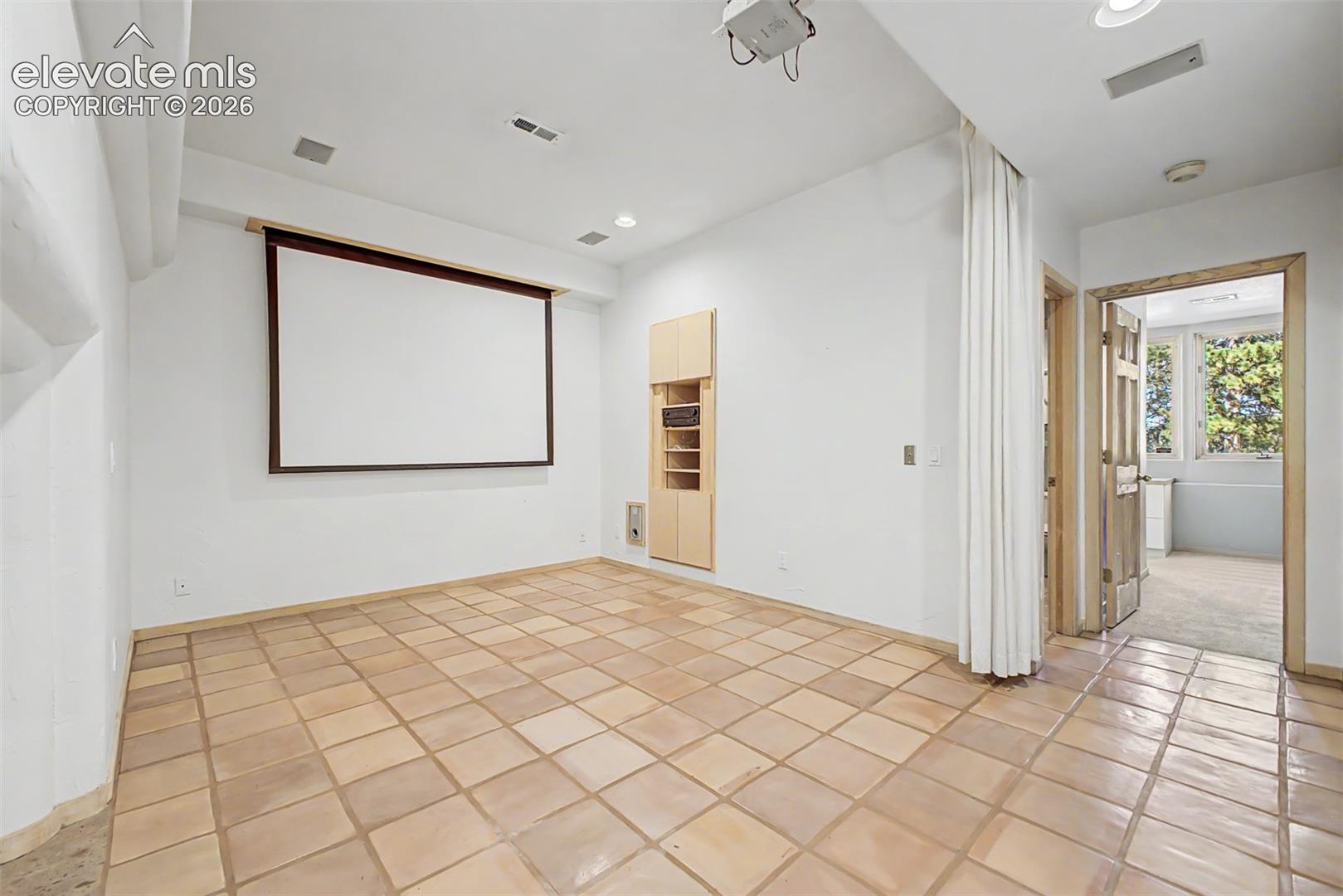 Media room with a projection screen, ceiling-mounted projector, and built-in wood-finish cabinetry