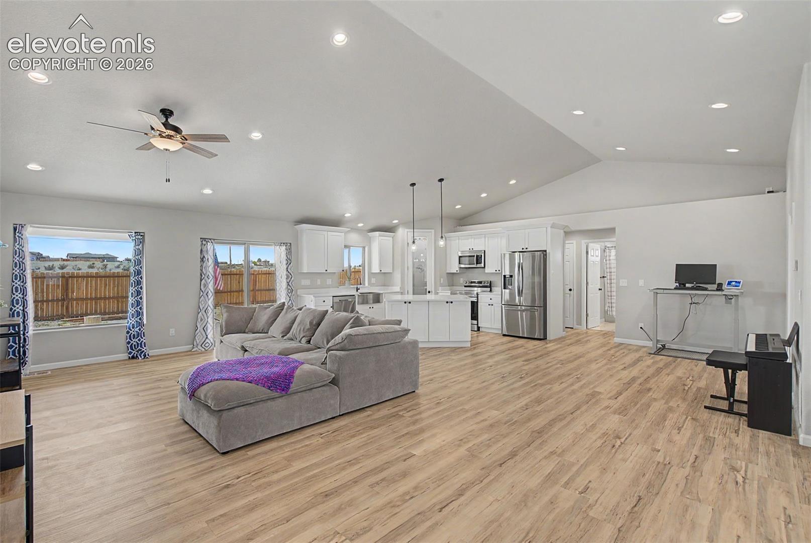 Open-concept living space featuring wood-finish flooring, vaulted ceilings, and recessed lighting