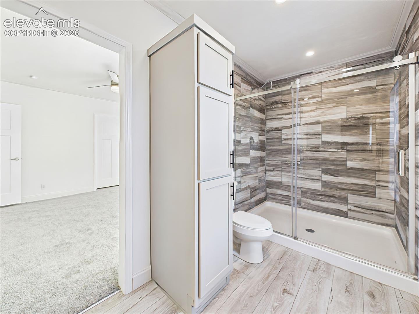 Spacious walk-in shower with full tile surround and built-in linen cabinetry.