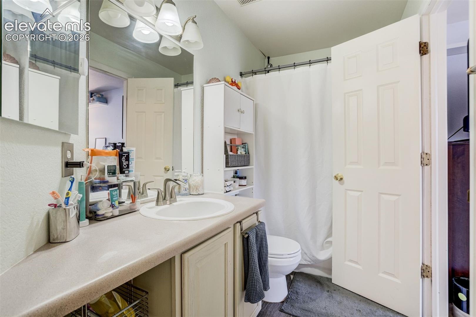 Vanity with an integrated sink, brushed nickel faucet, and a wall-mounted light fixture