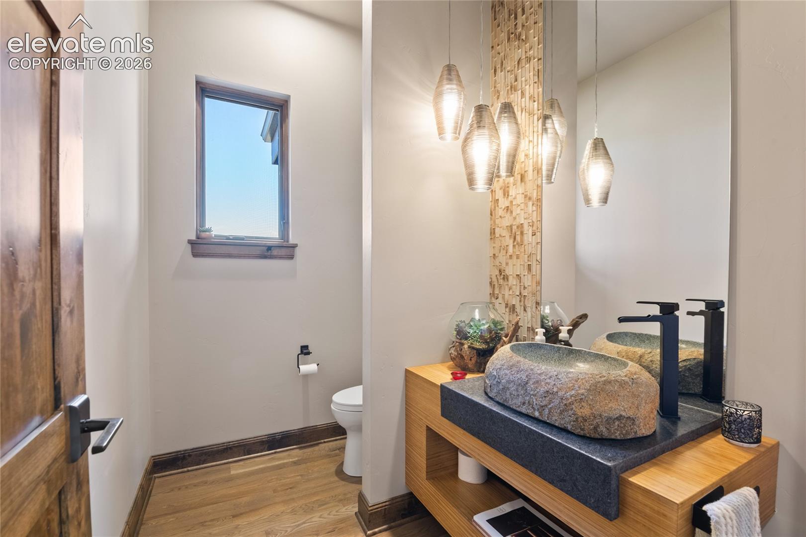 Designer powder room featuring dual natural stone vessel sinks, mosaic tile accent, custom pendant lighting, and a live-edge wood vanity.