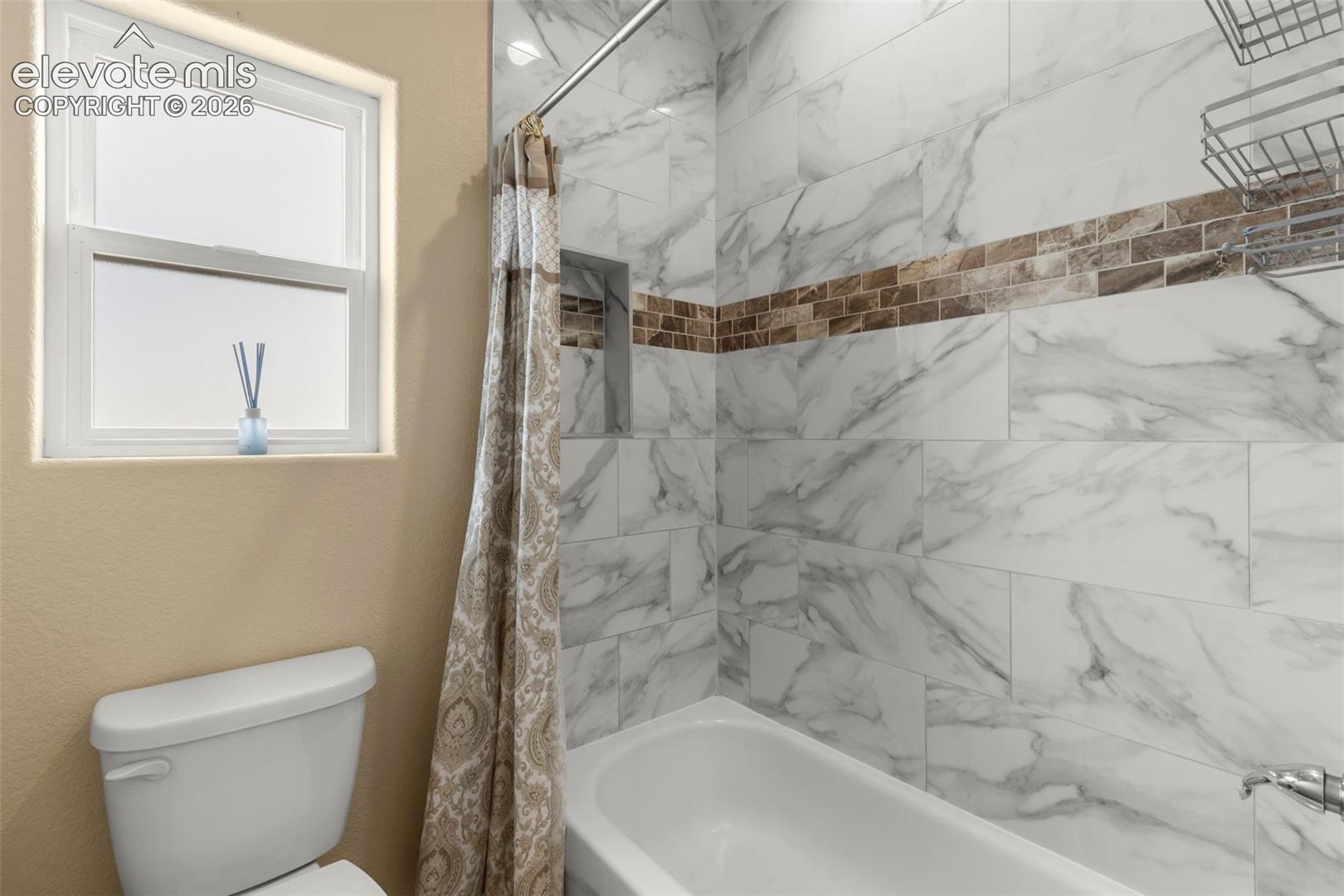 Full-height tile shower surround with integrated wall niche, decorative glass tile inlay, sliding curtain rod, and single-hung window