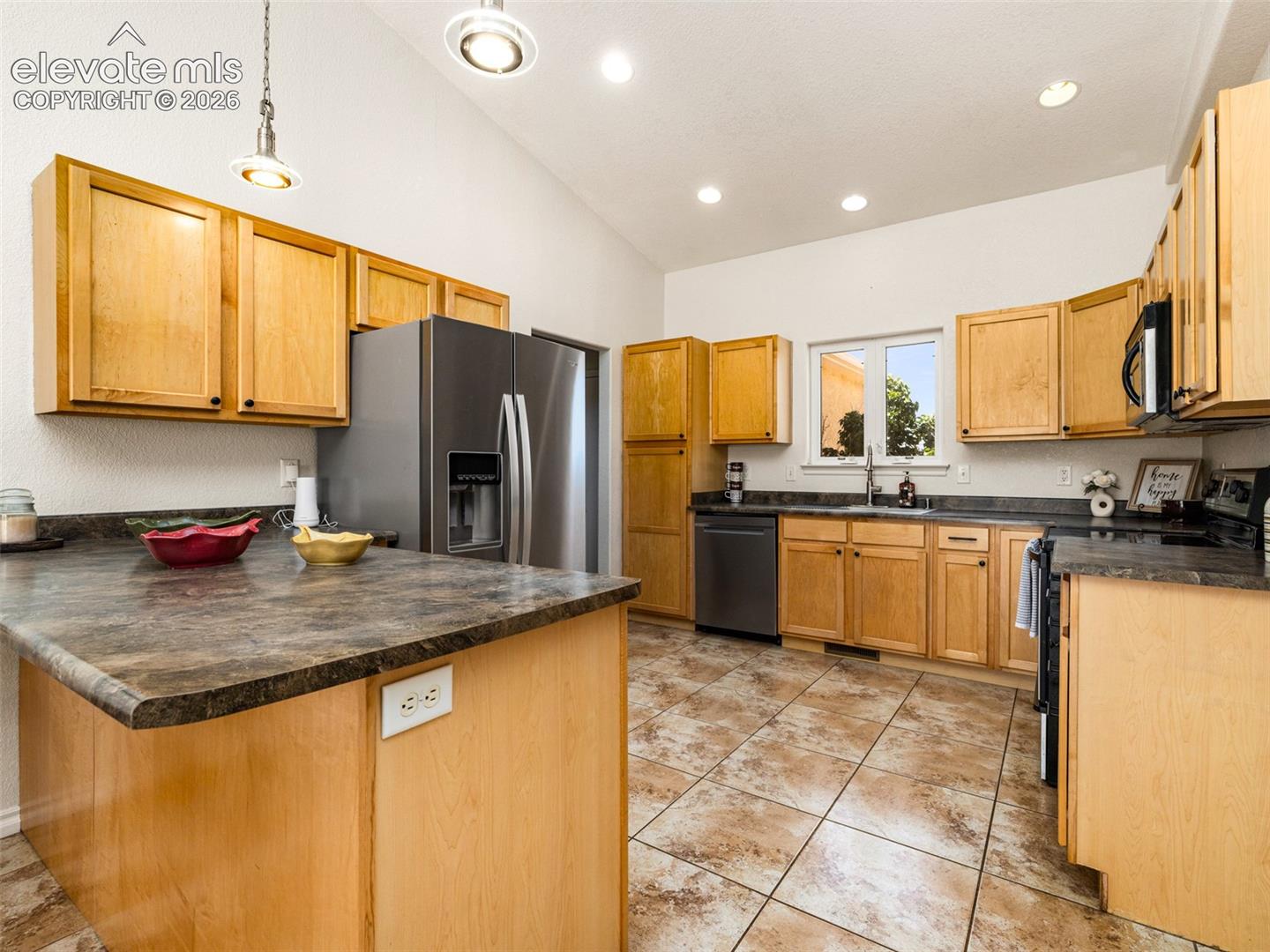 Vaulted ceilings, recessed lighting, wood cabinetry, stainless steel appliances, and tiled flooring