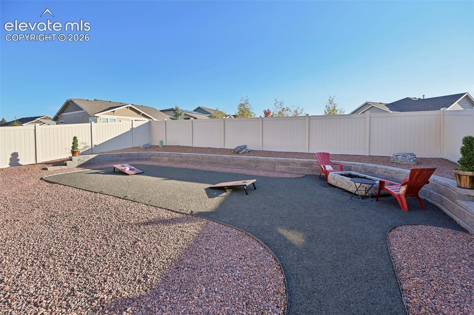 Multi-level backyard featuring a fire pit, privacy fencing, and stone hardscaping