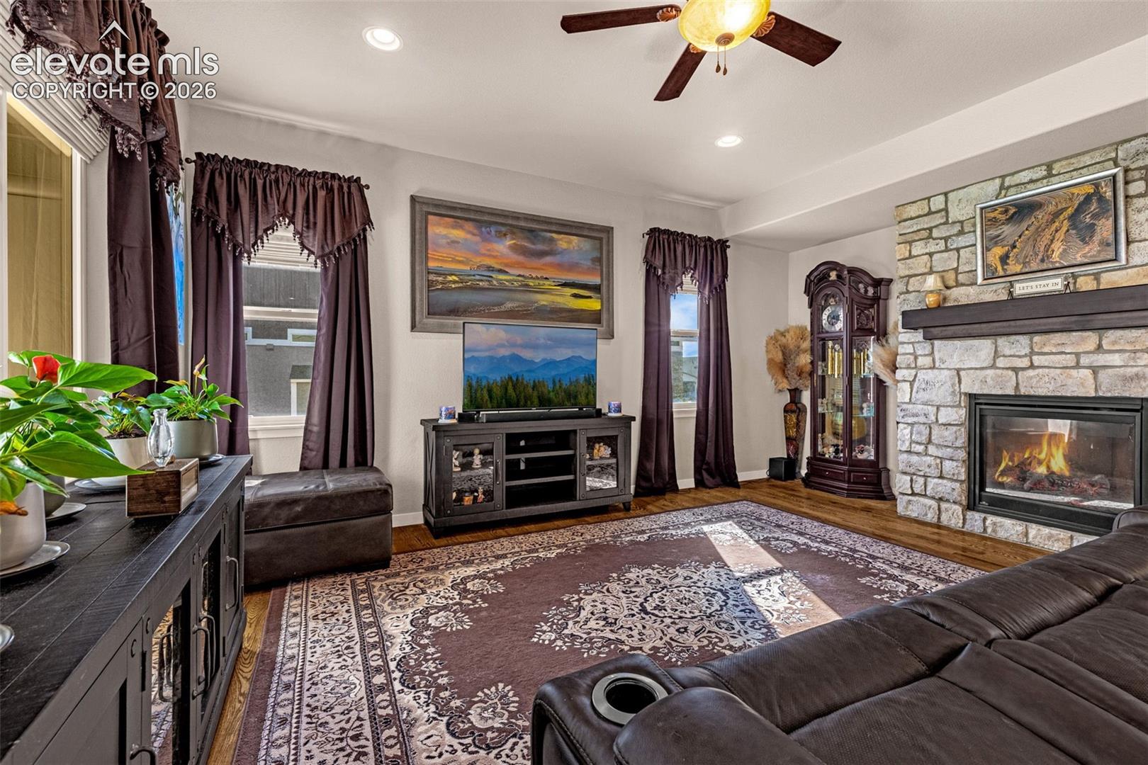 Living area featuring a floor-to-ceiling stone fireplace with a dark wood-finish mantel, wood-finish flooring, and recessed lighting