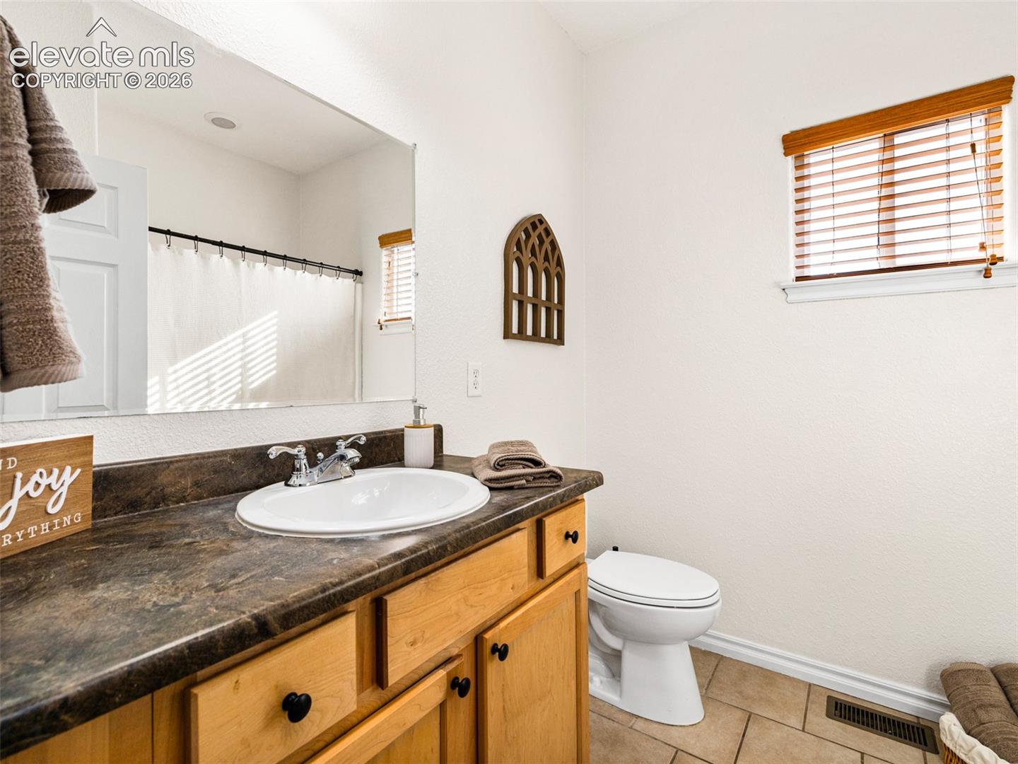 White vanity with a laminate countertop, undermount sink, and chrome faucet