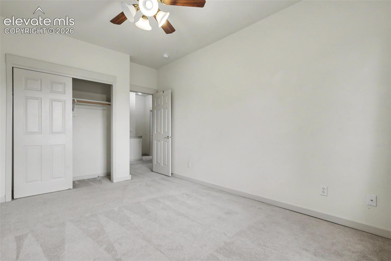 Carpeted room featuring a ceiling fan with integrated lighting, a closet with bi-fold paneled doors, and direct access to an additional interior space