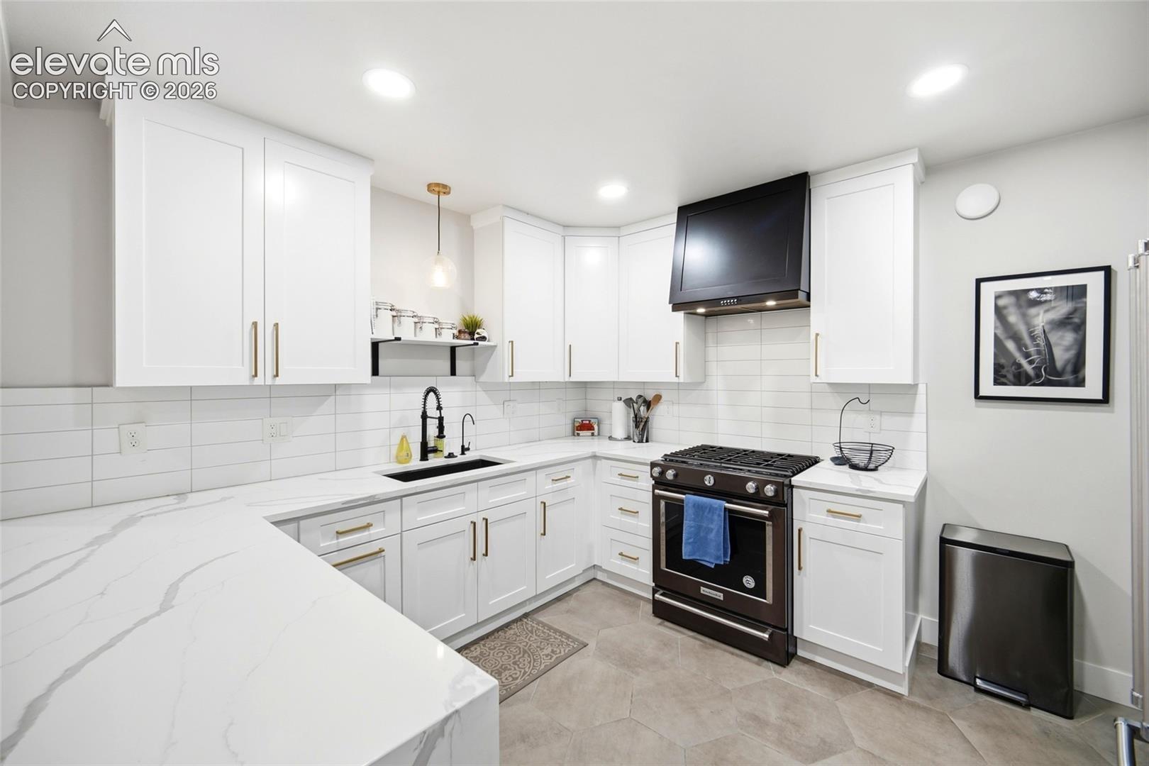 The kitchen's show-stopping details include a black undermount sink, a black pull-down faucet, a high-end range hood and brass cabinet pulls. 