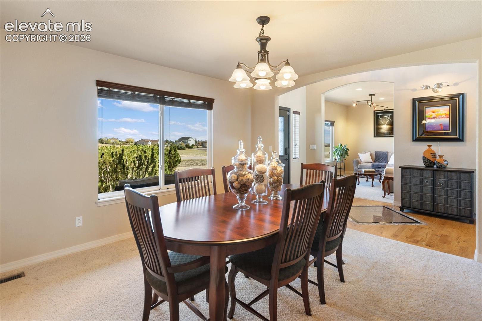Dining area featuring a five-light chandelier, carpeted flooring, and a large window
