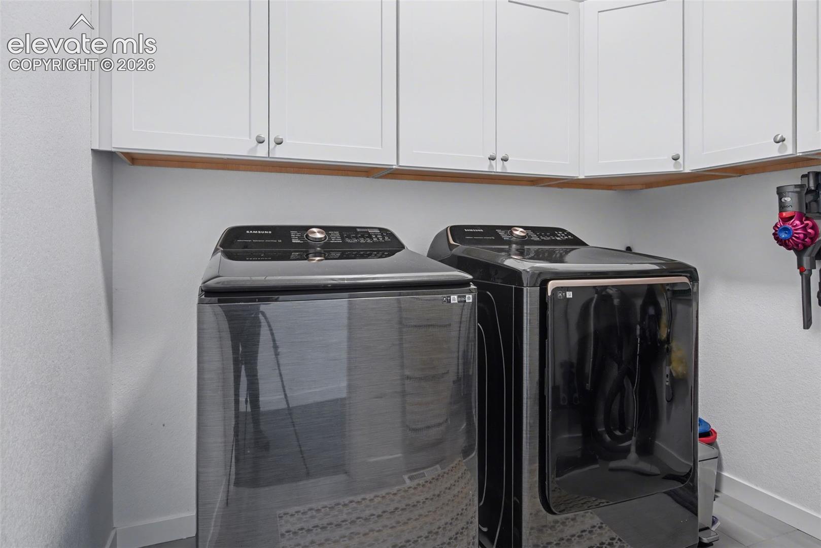 Laundry room with a textured wall, washer and dryer, and cabinet space