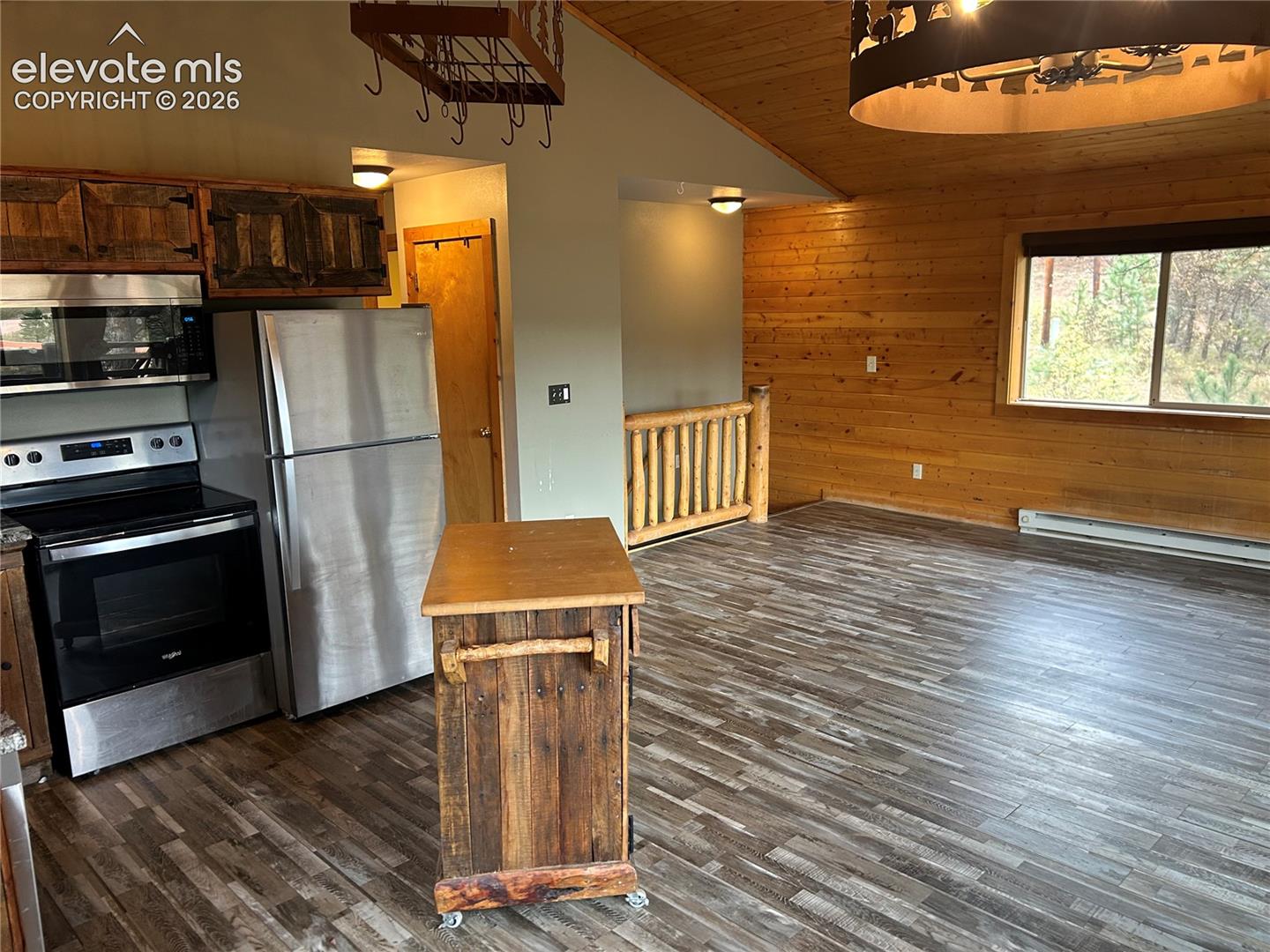 Kitchen featuring stainless steel appliances, wood-paneled walls, vaulted ceiling with wood planking, and wood-finish flooring