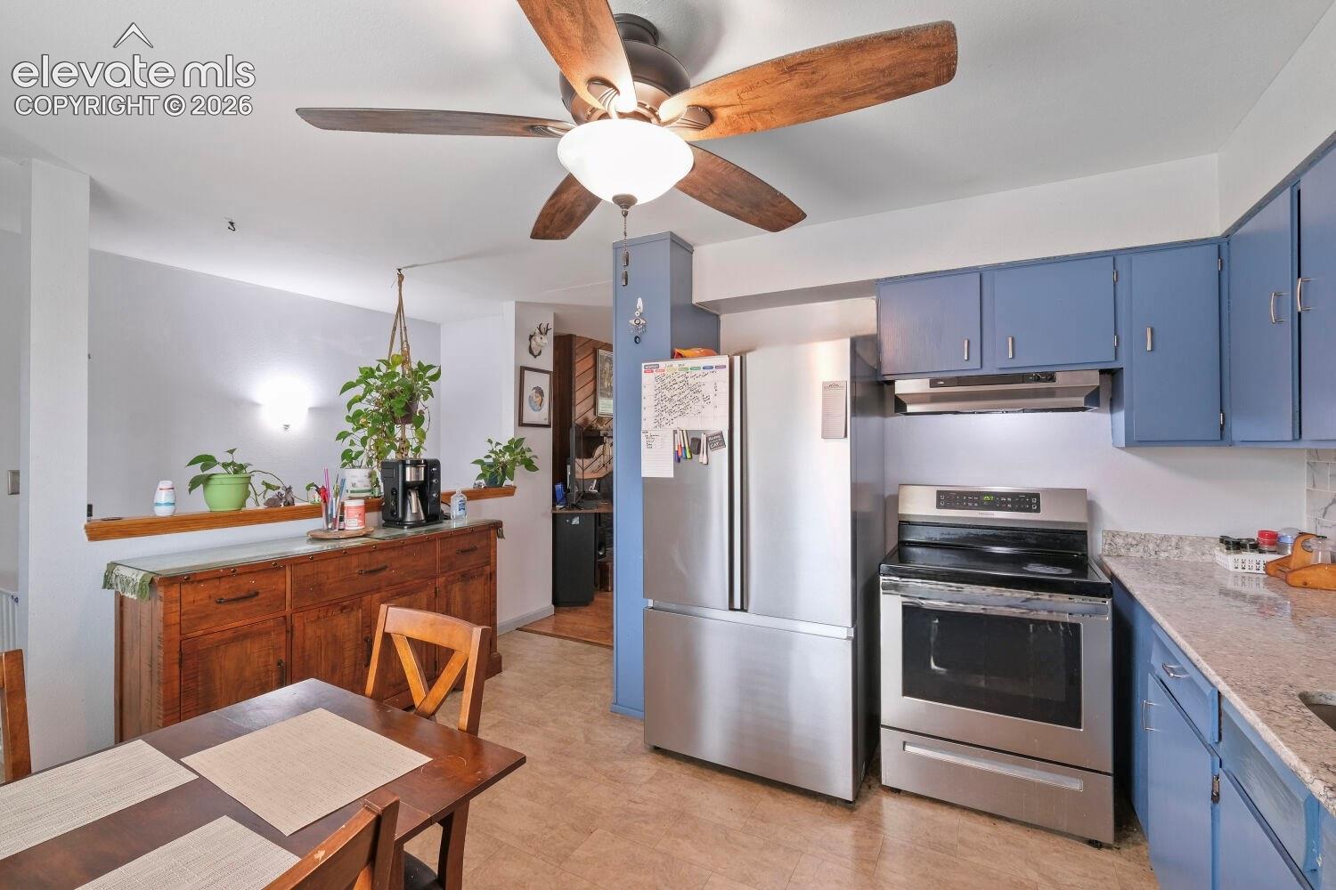 Kitchen and dining area featuring a wood-finish dining table and a ceiling fan with wood-finish blades