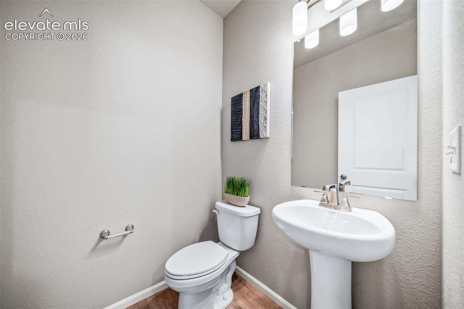 Pedestal sink with a polished chrome faucet, rectangular mirror, and overhead vanity lighting
*photos of a model home*
