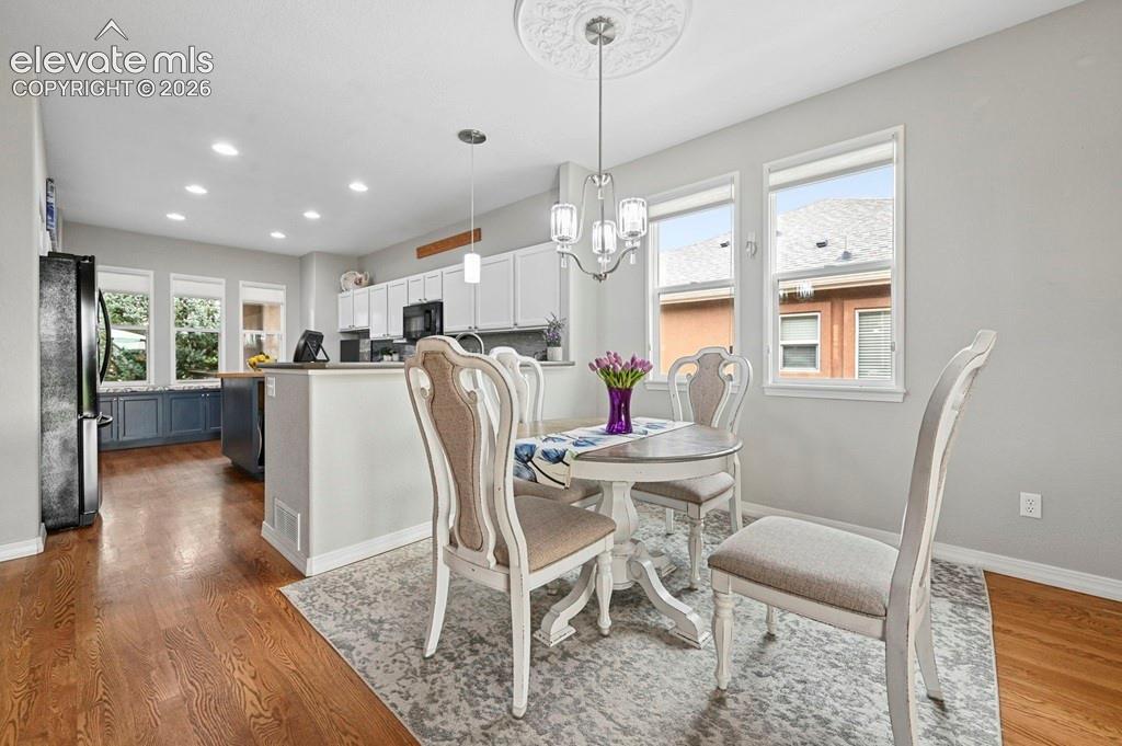 Recessed lighting, wood-finish flooring, white cabinetry, kitchen island with wood countertop, and a chandelier with ceiling medallion