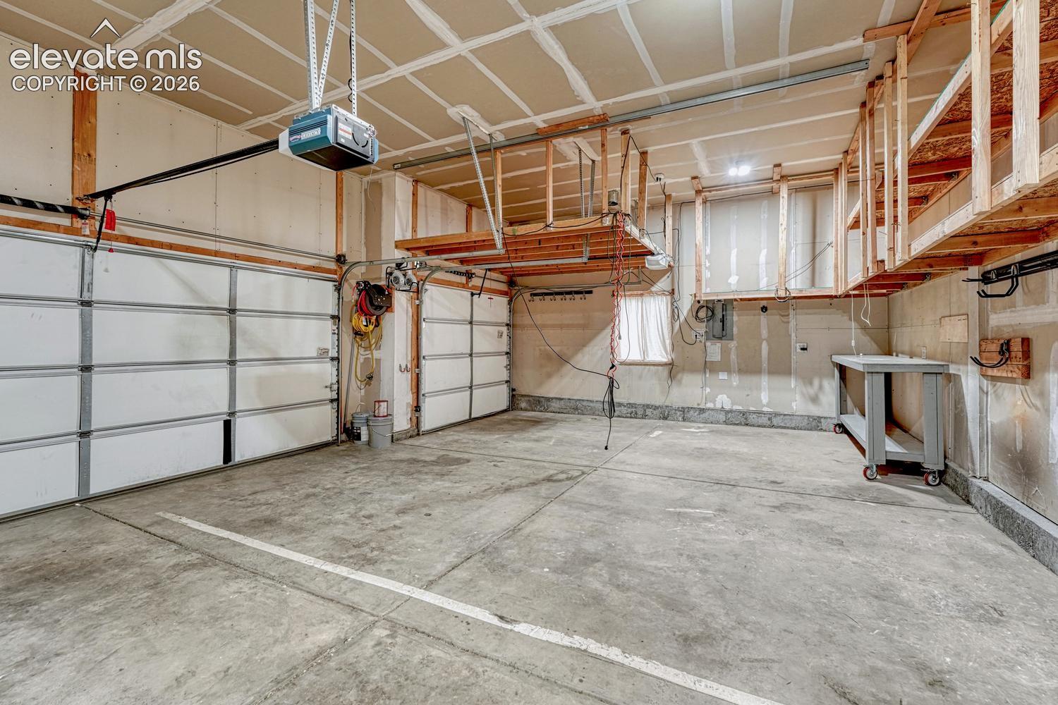 3-car attached garage with custom ceiling storage, work bench, and door opener.