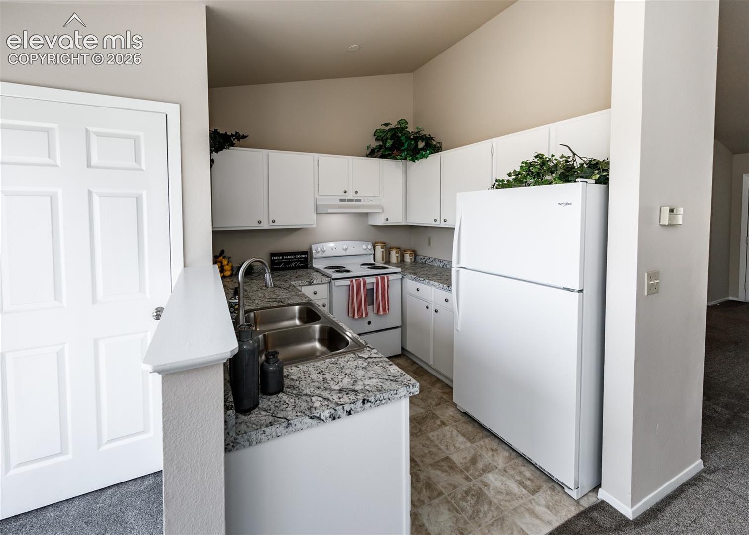 Kitchen featuring white cabinetry, white appliances, a double basin sink, and stone-finish countertops
