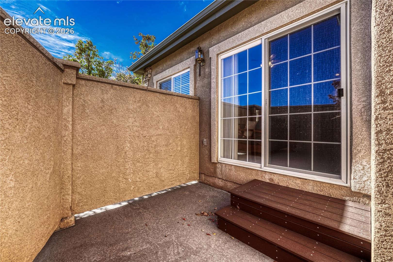 Walk out from the great room to your private, walled concrete patio with composite steps, offering a secluded outdoor sanctuary
