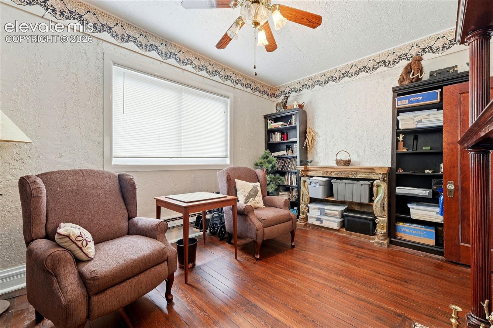 Hardwood flooring, painted walls, ceiling fan, window with blinds, and built-in shelving