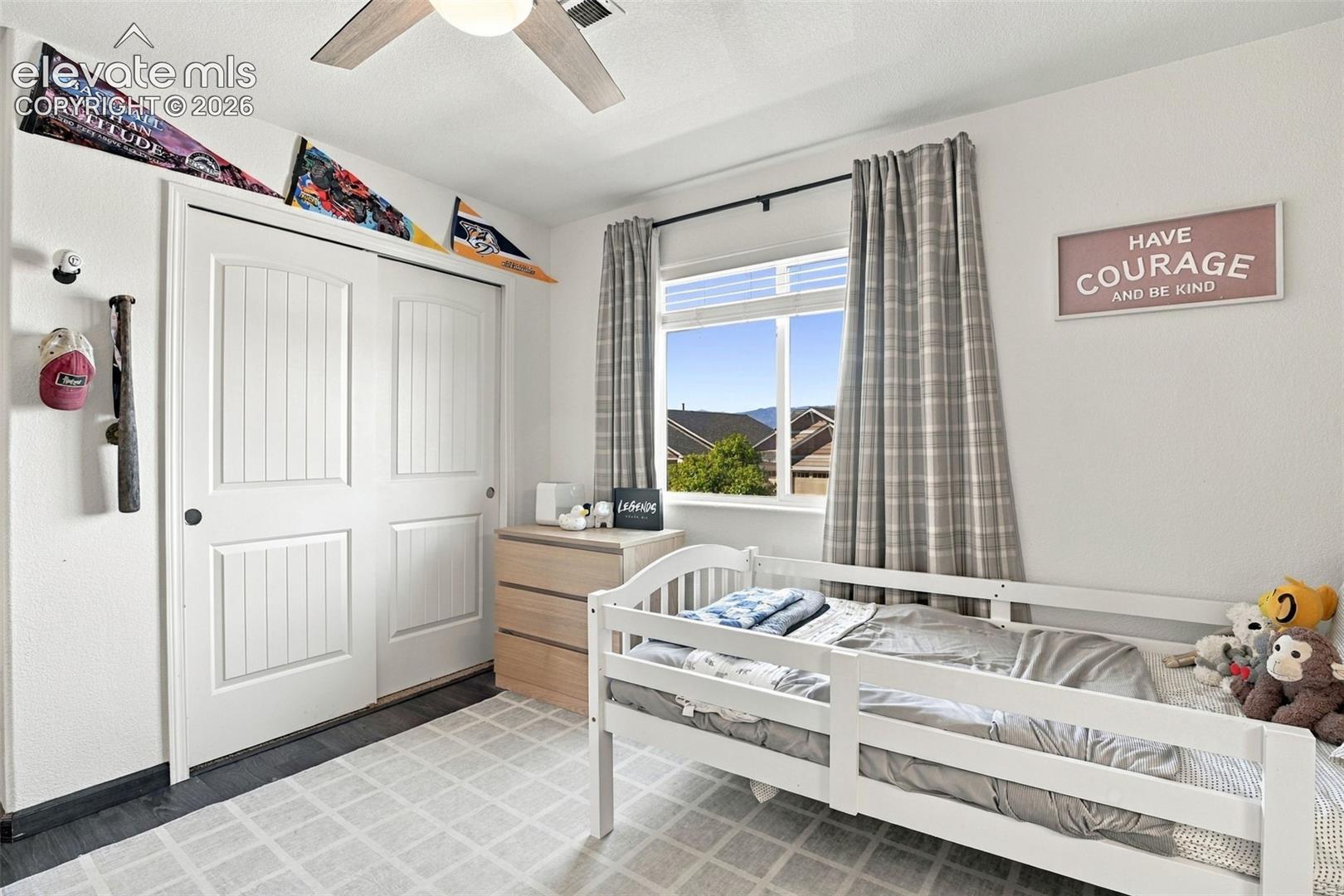 Built-in sliding closet doors with vertical paneling, light wood-finish flooring, and a ceiling fan with light fixture