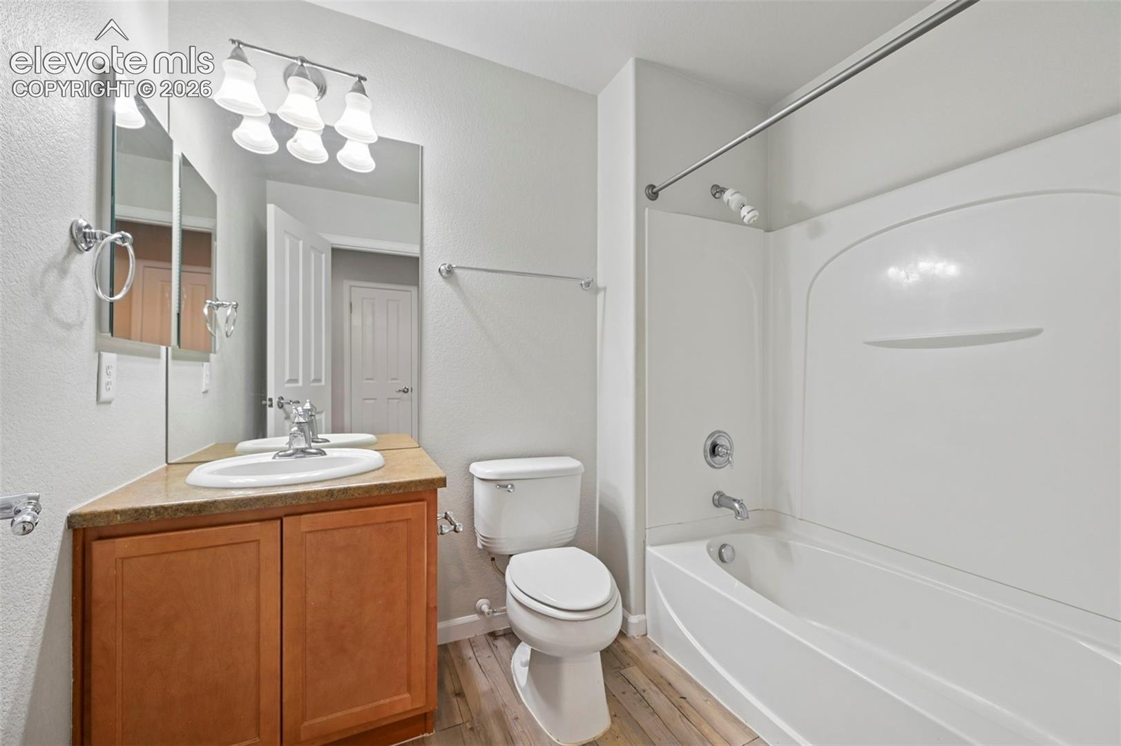 Bathroom featuring a wood-finish vanity with an integrated sink, a large mirror, and a three-light fixture