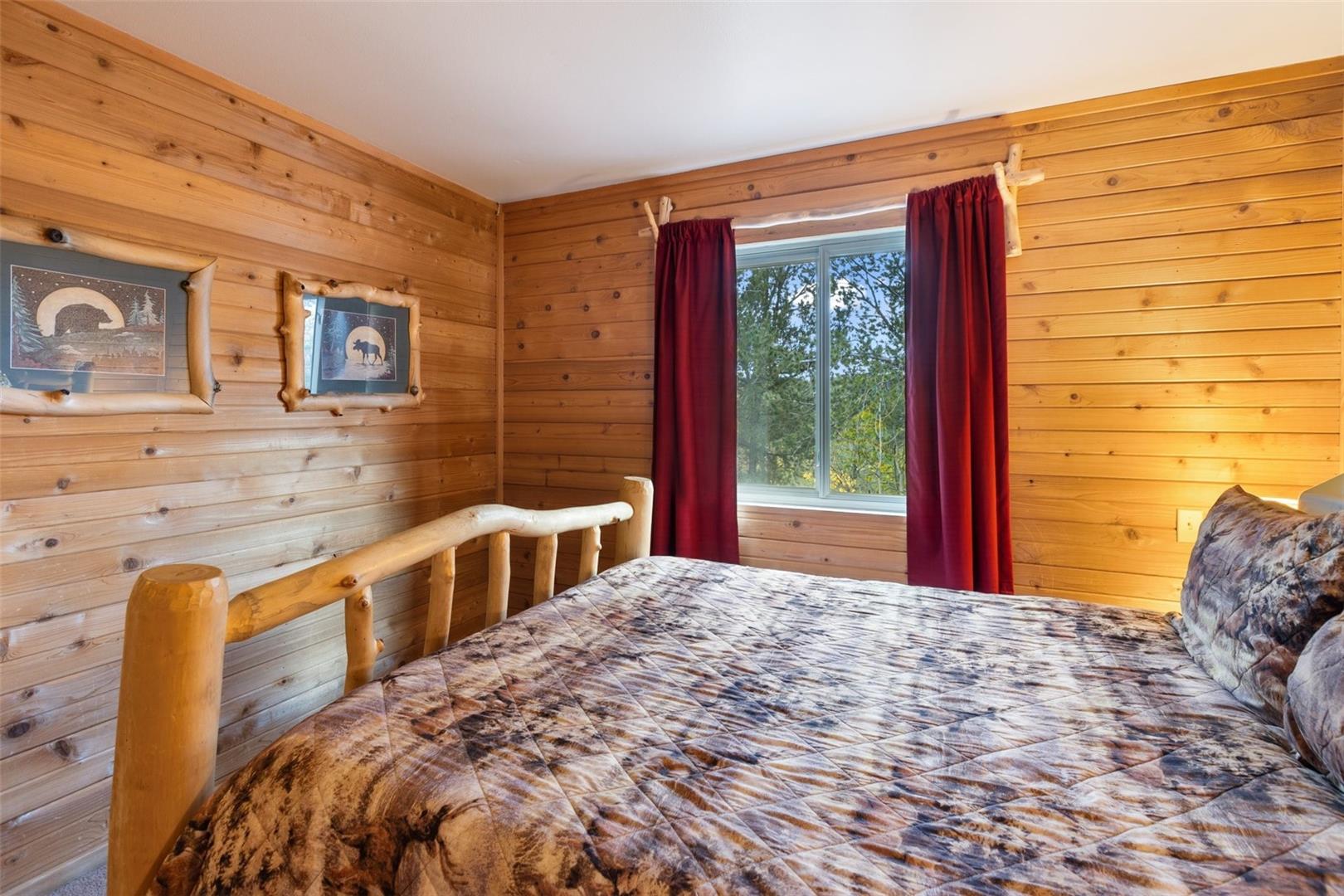 Natural wood paneling throughout, built-in window with outdoor scenery, and a rustic wood-frame bed