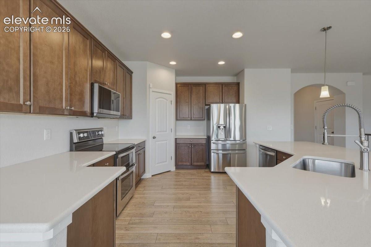 Kitchen featuring wood-finish flooring, recessed lighting, and an arched doorway