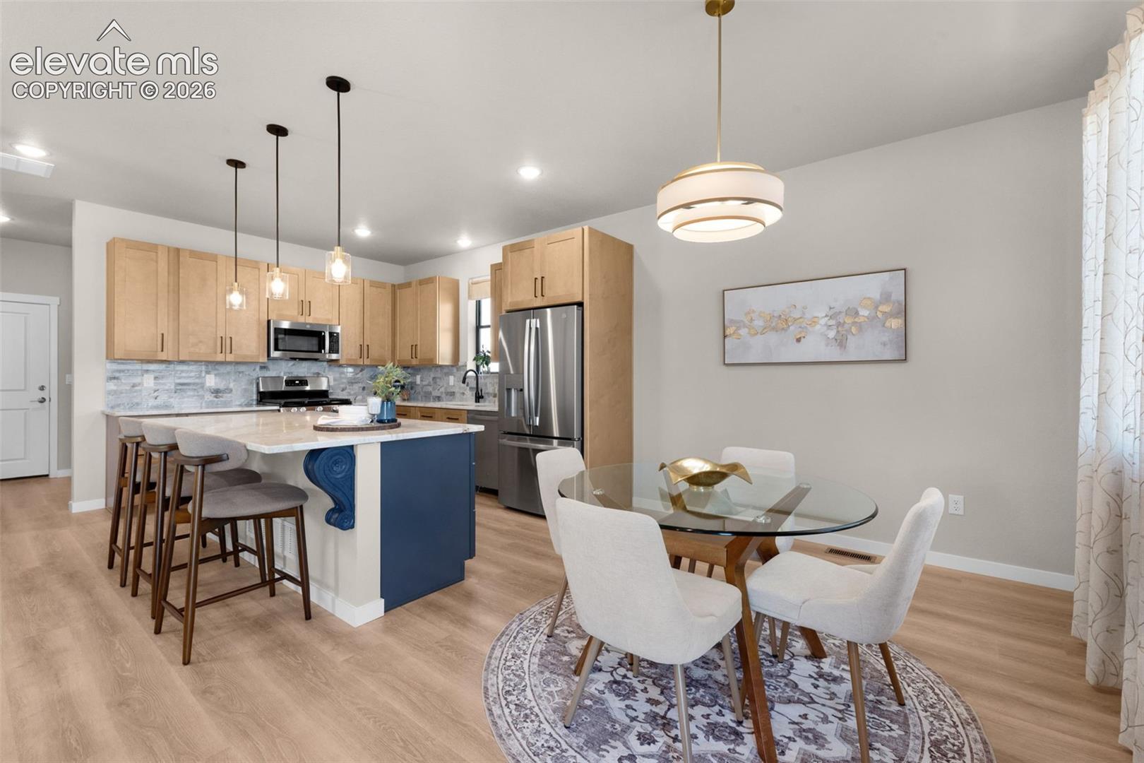 Open-concept kitchen and dining area featuring wood-finish flooring, recessed lighting, and a kitchen island with pendant lighting