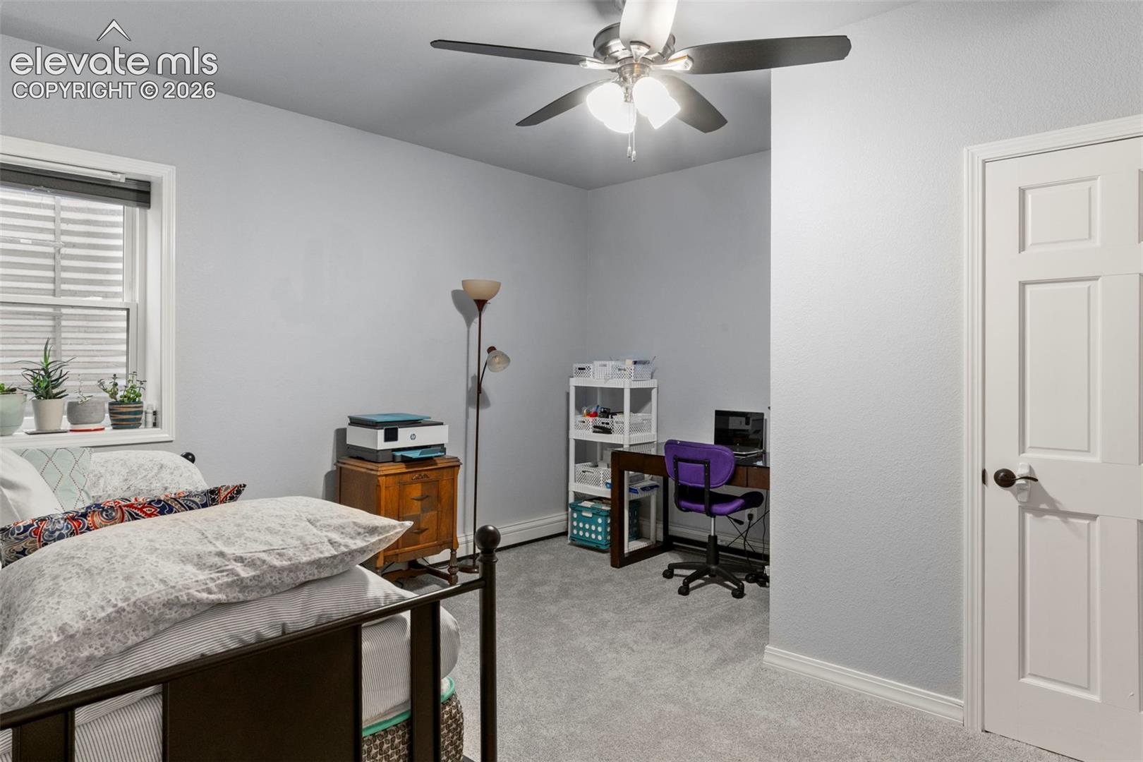 Bedroom featuring light carpet, ceiling fan, and a desk