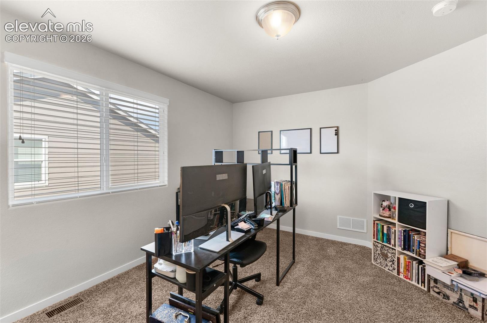Neutral-toned interior space featuring neutral wall-to-wall carpeting, a multi-pane window with horizontal blinds, and a semi-flush mount ceiling fixture