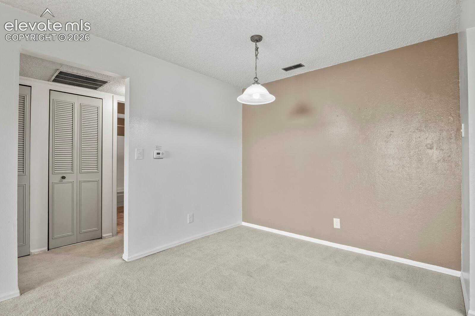 Interior dining space(could be a home office if needed) featuring neutral-toned carpeting, a dual-tone wall finish and a decorative pendant light fixture