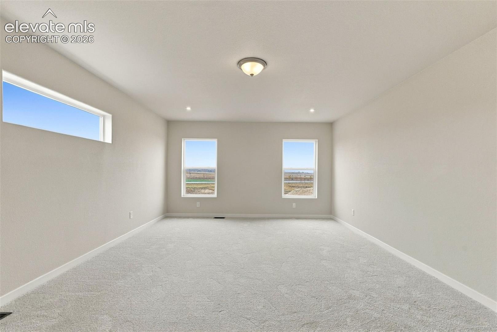 Neutral wall-to-wall carpeting, expansive horizontal window, dual vertical windows, and flush-mount ceiling lighting