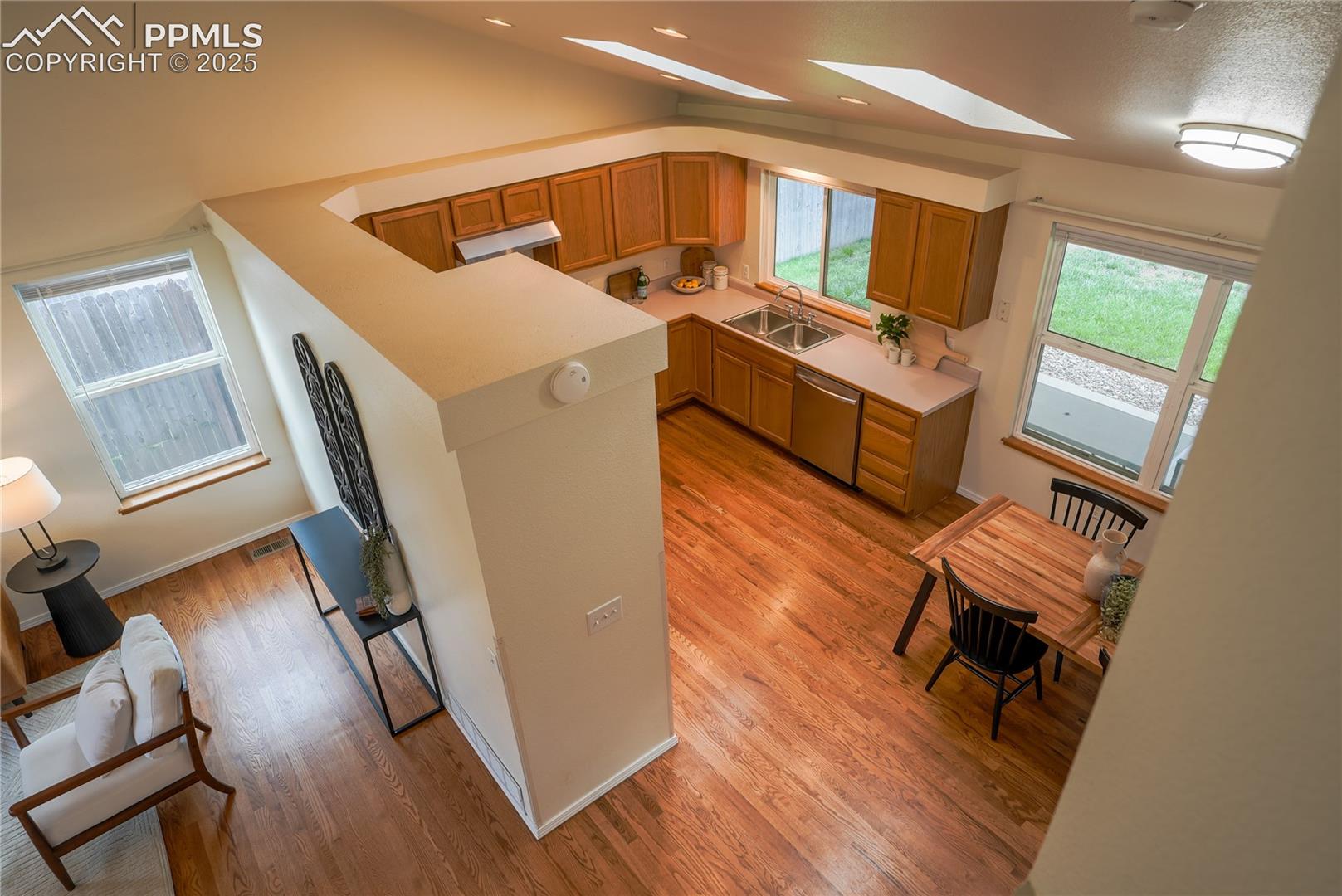 Kitchen with light countertops, light wood finished floors, stainless steel dishwasher