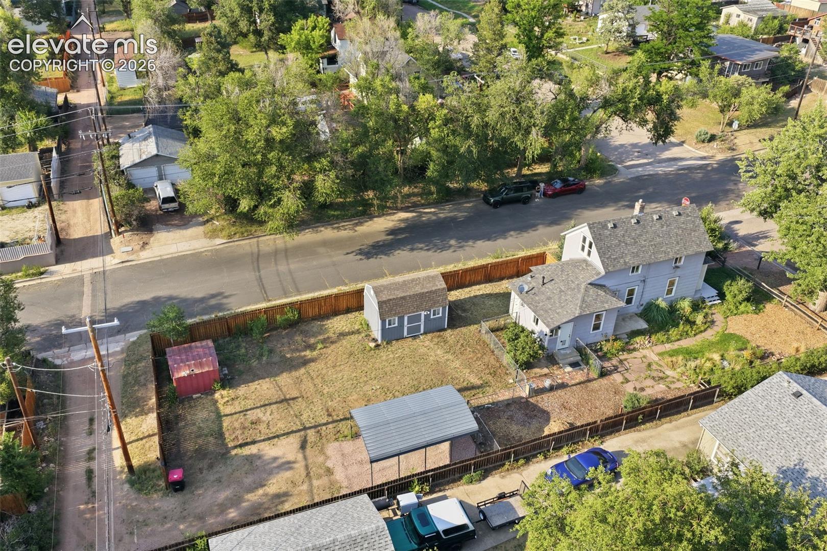 Property featuring a detached shed, an additional smaller red shed, a metal carport, and a fenced yard.