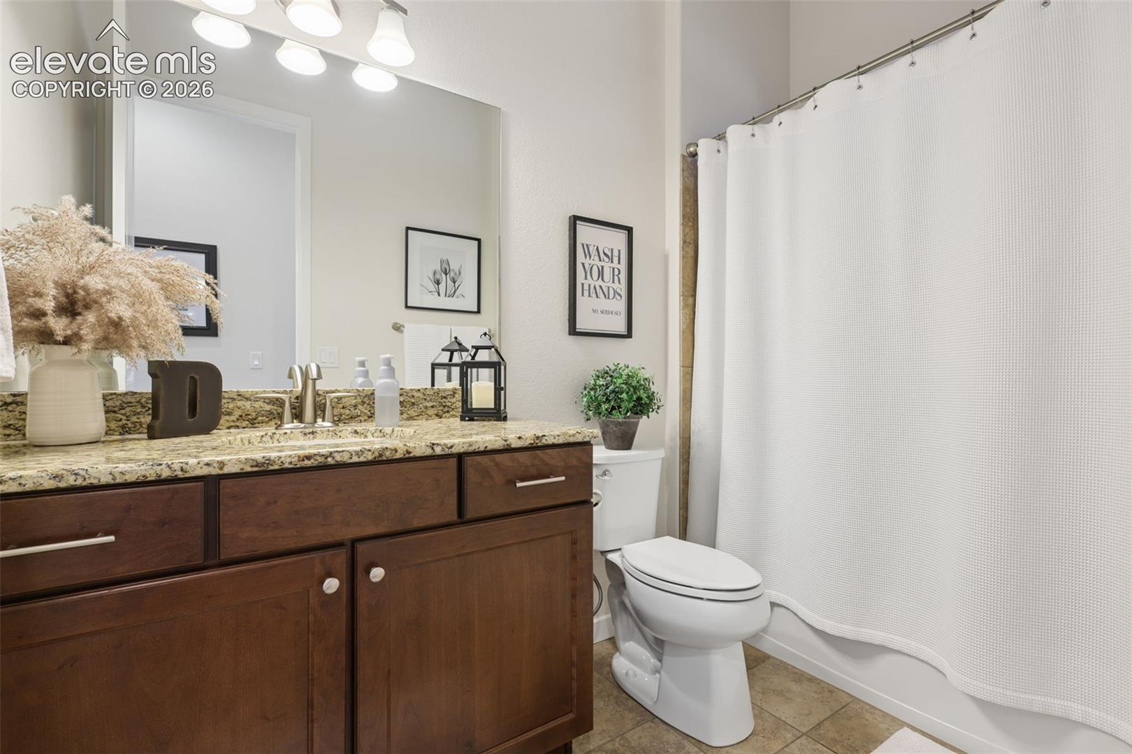 Vanity with a granite-style countertop, undermount sink, and wood-finish cabinetry