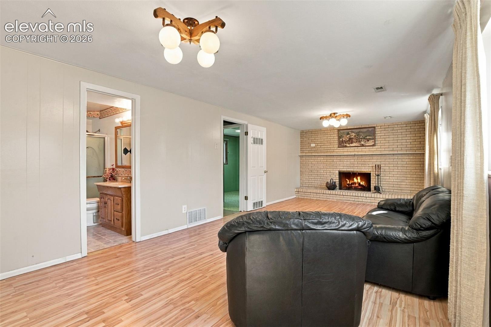 Wood-finish flooring throughout, masonry fireplace with a brick surround, and multi-light flush-mount fixtures