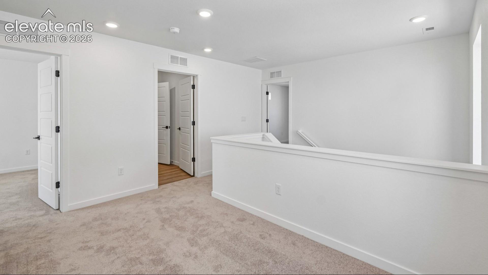 Neutral-toned carpet flooring, recessed lighting, and solid-core paneled doors