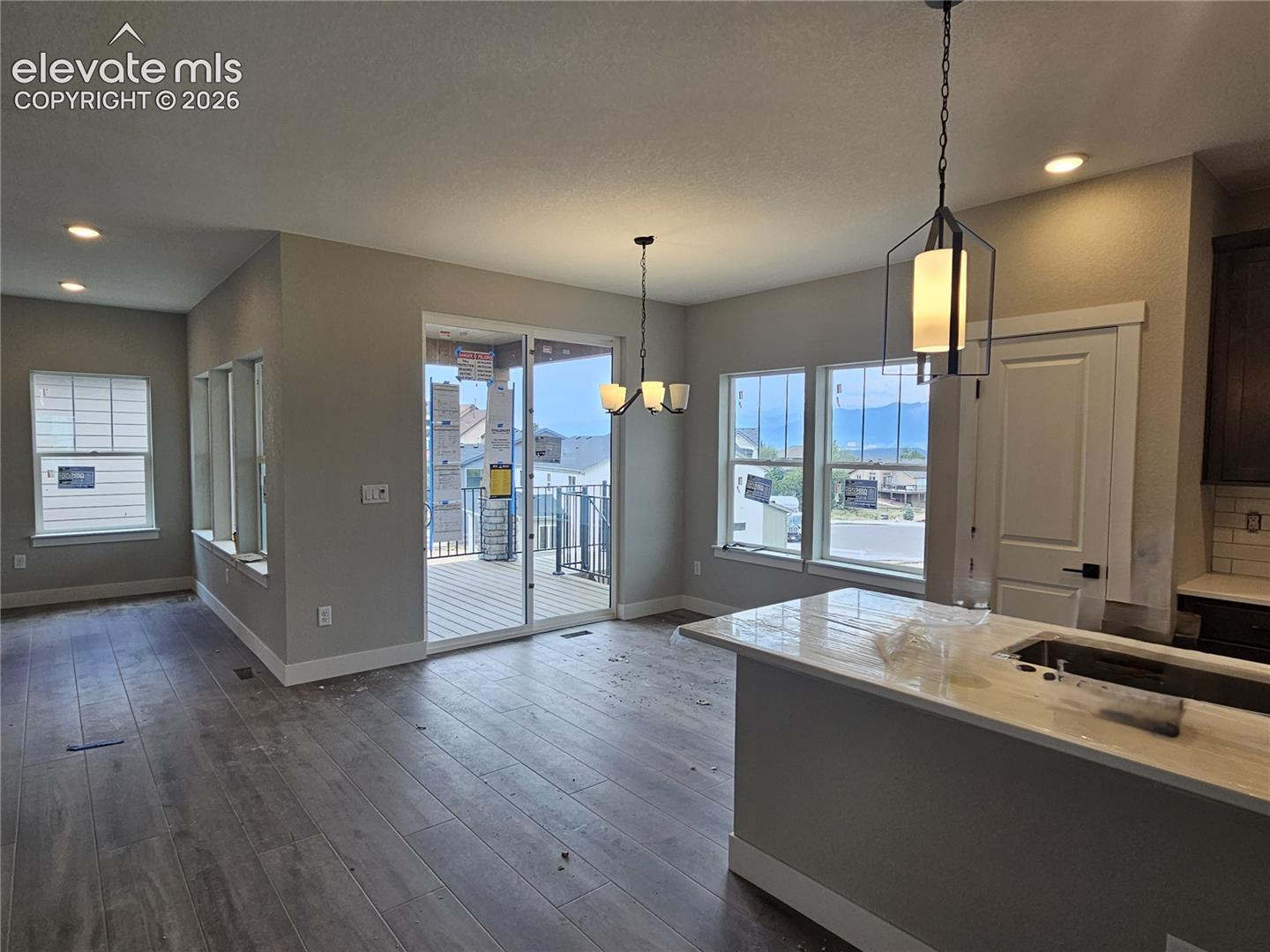 living room with recessed lighting and cutout pass-through, dining area with chandelier and sliding glass door to deck, kitchen island with pendant light and sink
