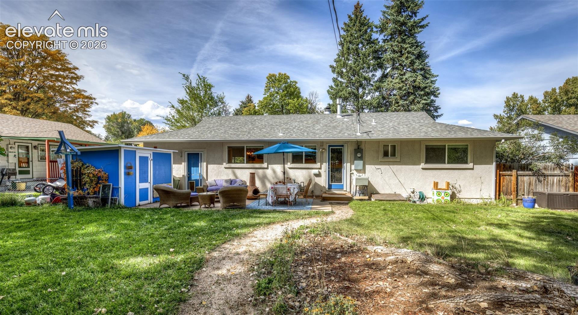 Expansive backyard featuring a concrete patio, a detached storage shed, and mature trees