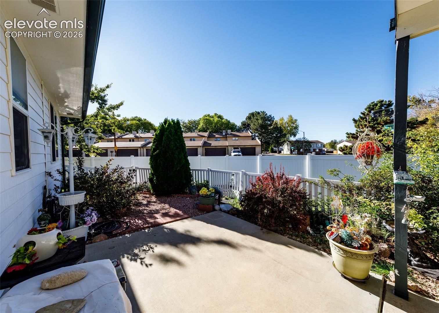 Concrete patio featuring a white vinyl privacy fence and low-maintenance stone landscaping