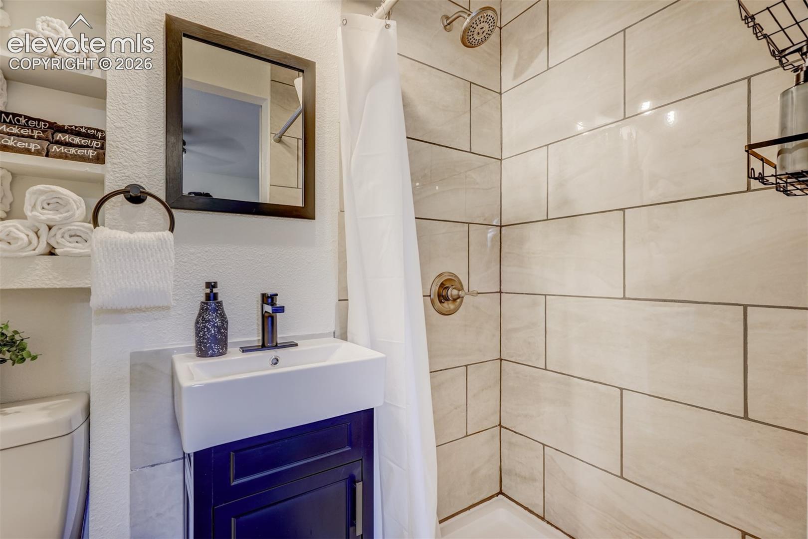White ceramic subway tile shower surround with bronze fixtures