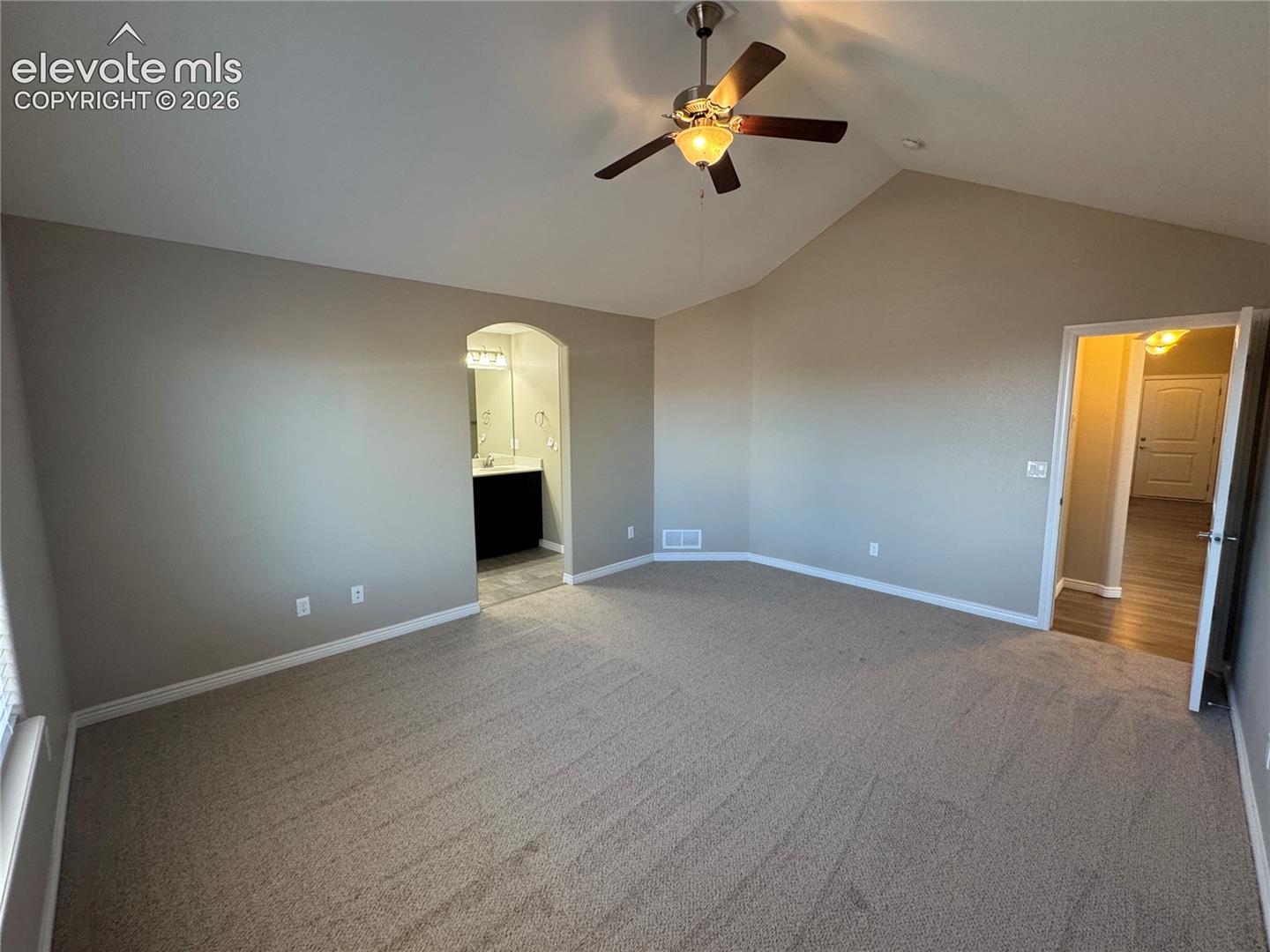 Vaulted ceilings featuring a central brushed-metal ceiling fan with integrated lighting and neutral wall-to-wall carpeting