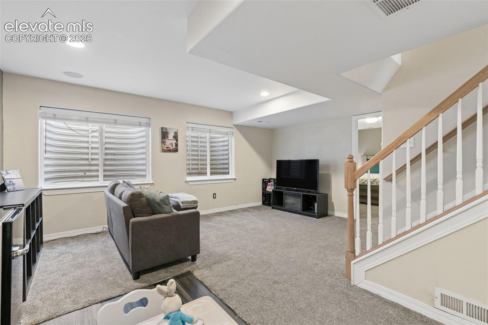 Carpeted flooring, recessed lighting, and a white and wood-finish staircase