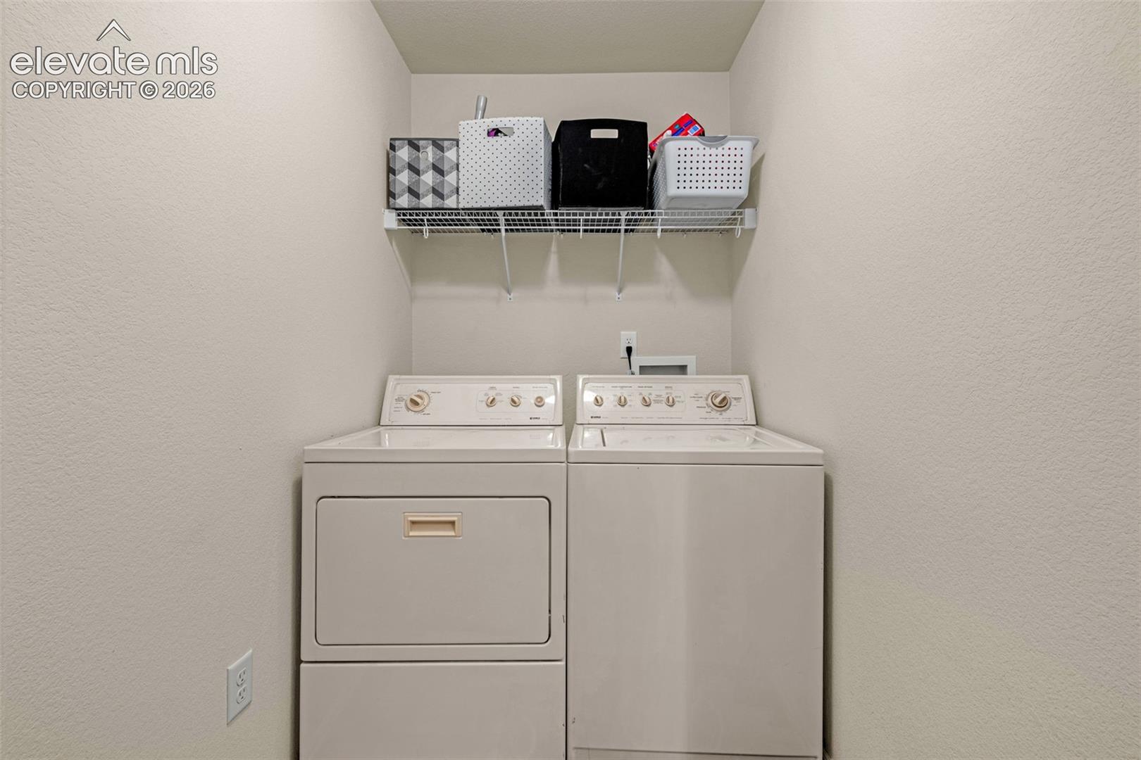 Dedicated laundry space featuring a white top-load washing machine and front-load dryer