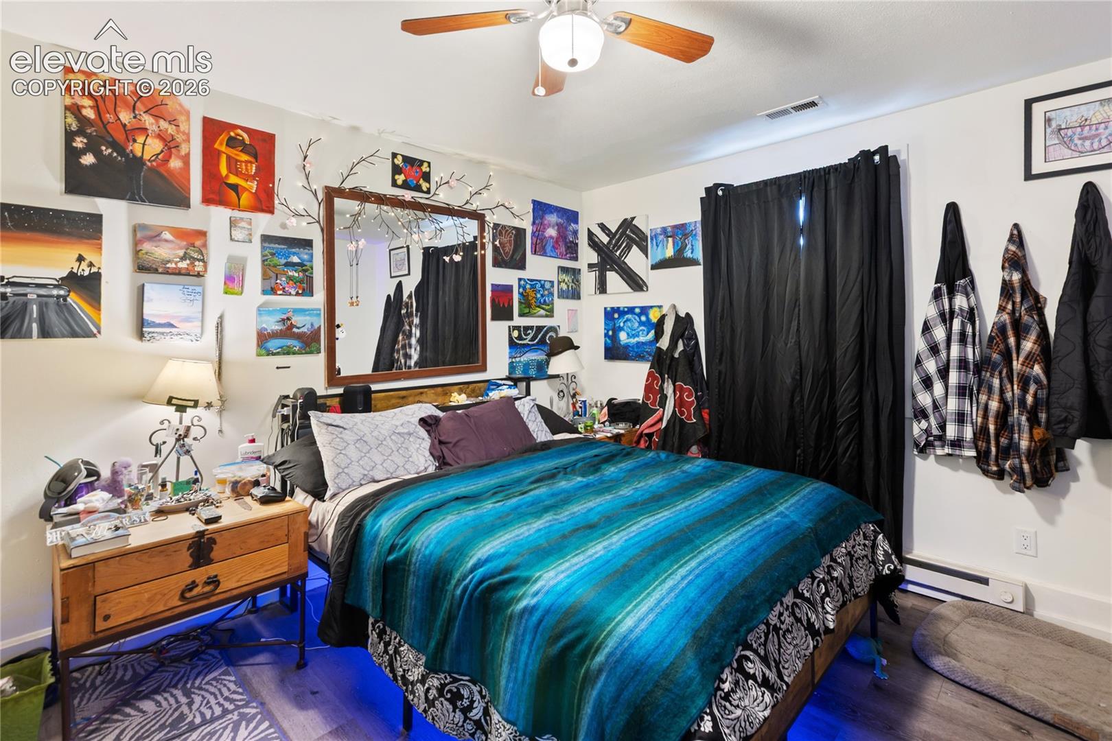 Room featuring wood-finish flooring, a wall-mounted mirror, and a ceiling fan with light fixture
