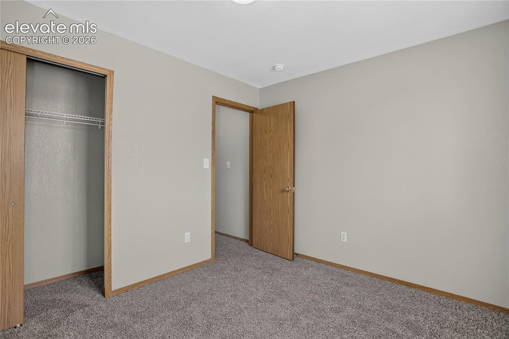 Wall-to-wall carpeting with light gray walls, wood-finish trim, and natural wood doors