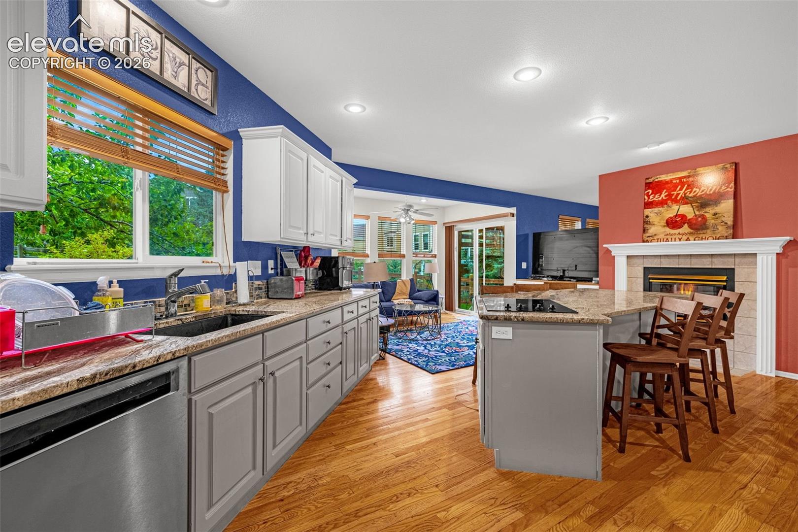 Kitchen featuring wood-finish flooring, white upper cabinetry, gray lower cabinetry, and a granite-style countertop