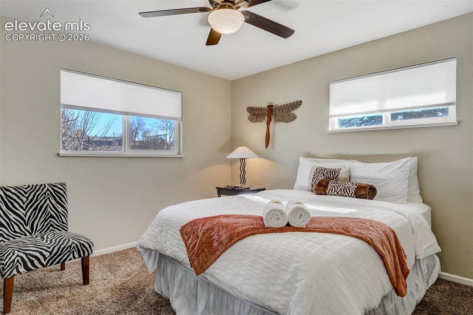 Ceiling fan with integrated lighting, two windows with blinds, and textured wall finish